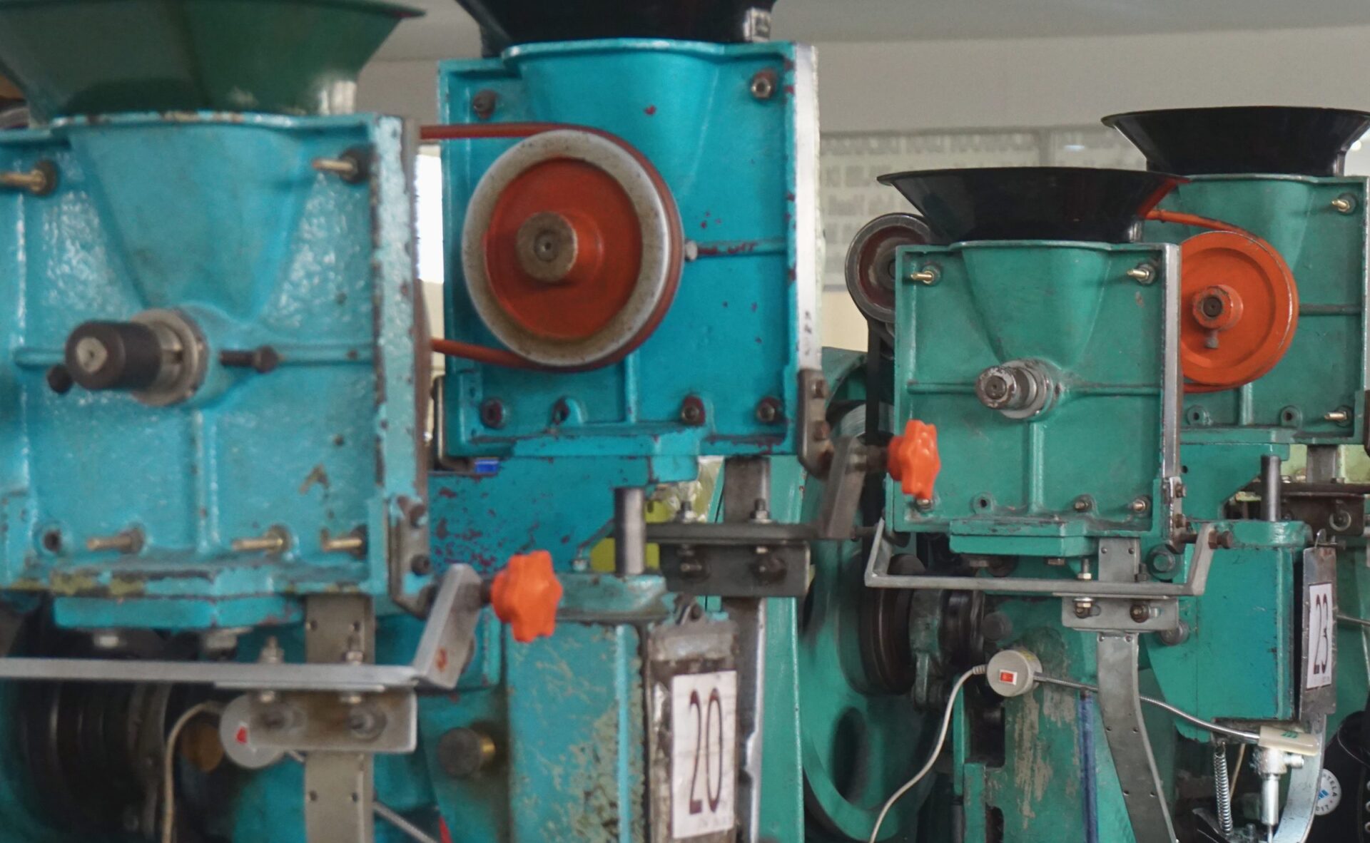 Deretan eyelet machine berwarna hijau toska dengan roda merah