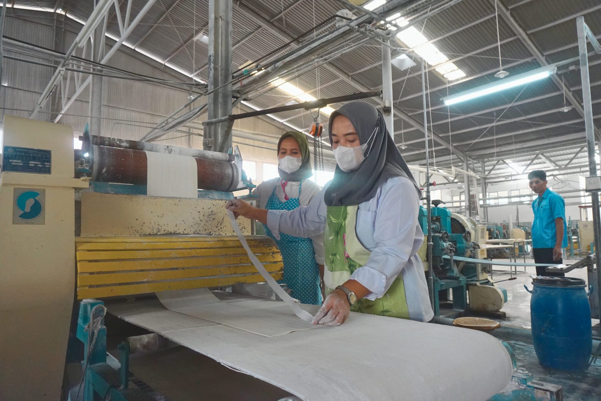 Operator merapikan lembaran karet dari calendar machine